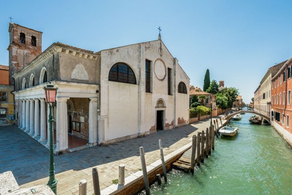 A canal with boats, a historic building with columns, and a bridge.