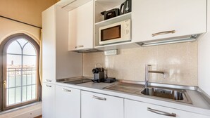 Una cocina moderna con armarios blancos, un lavamanos de acero inoxidable, un microondas y una cafetera.