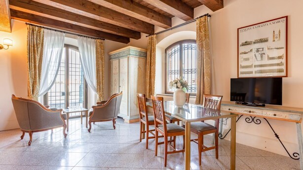 A dining area with a table, chairs, a television, and a decorative wall piece.