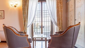 A room with two upholstered chairs, a small table, and a large window with curtains.