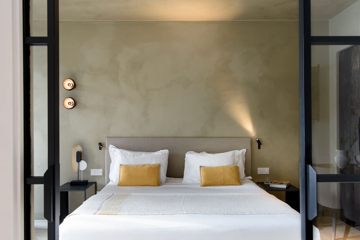 Een moderne hotelkamer met een groot bed, twee nachtkastjes, een wandlamp en een nachttafel.