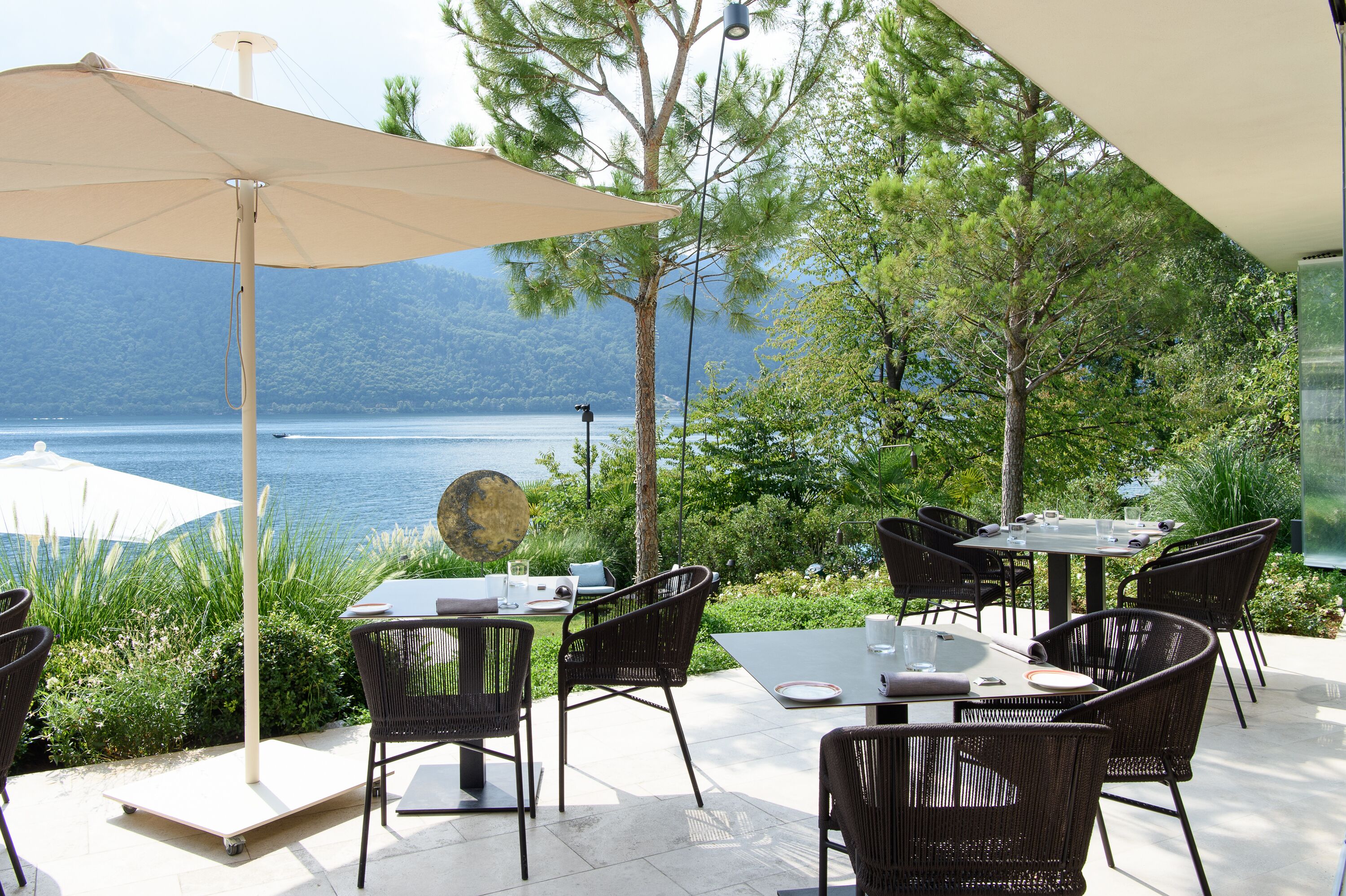 Un espace extérieur aménagé pour les repas, avec des tables et des chaises, donnant sur un lac.