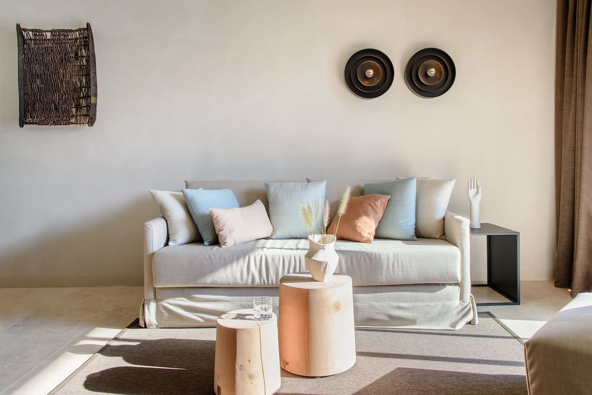 Een moderne woonkamer met een bank, twee bijzettafels en een wandlamp.