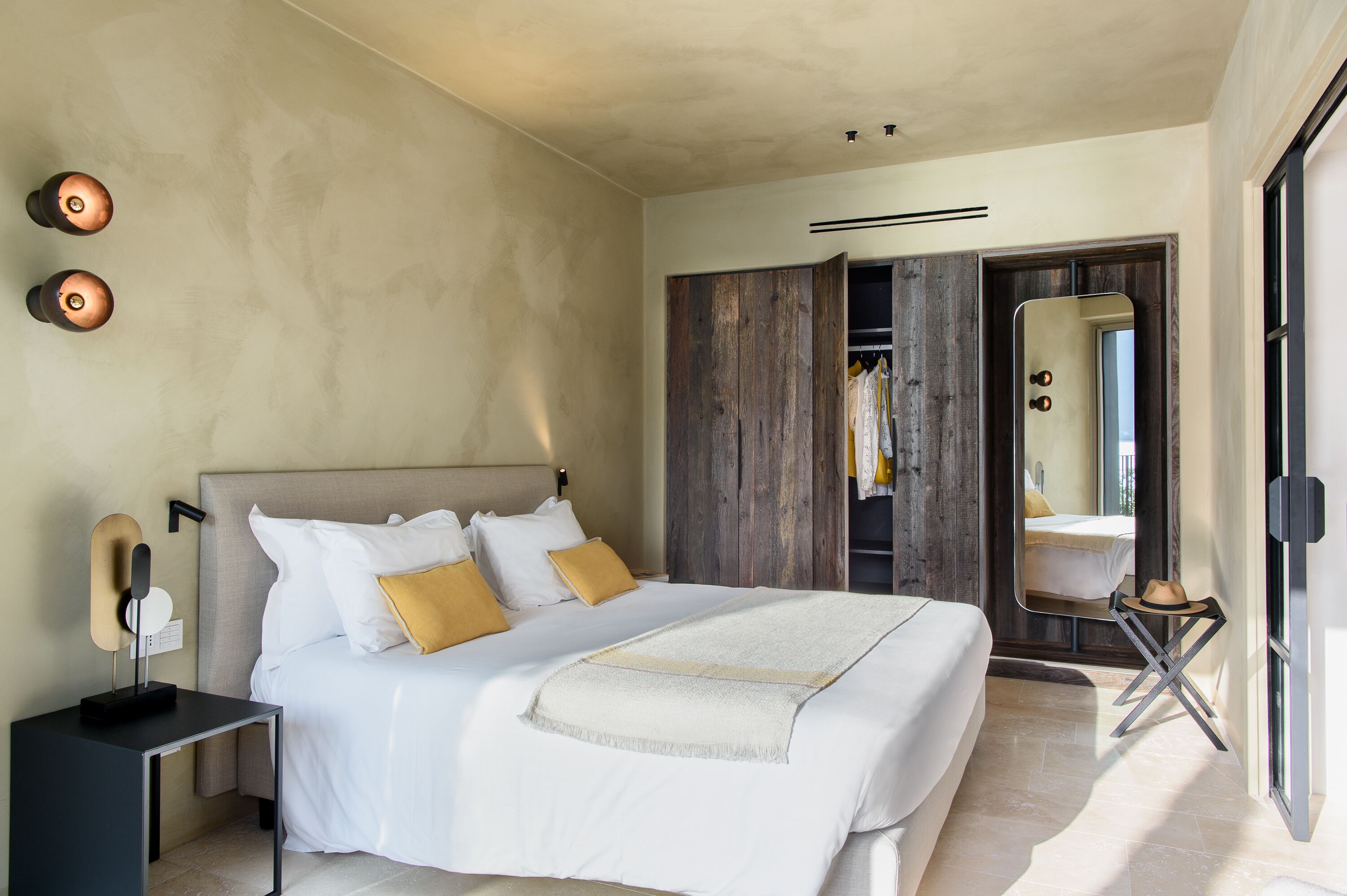A modern bedroom with a large bed, a wardrobe, and a mirror.