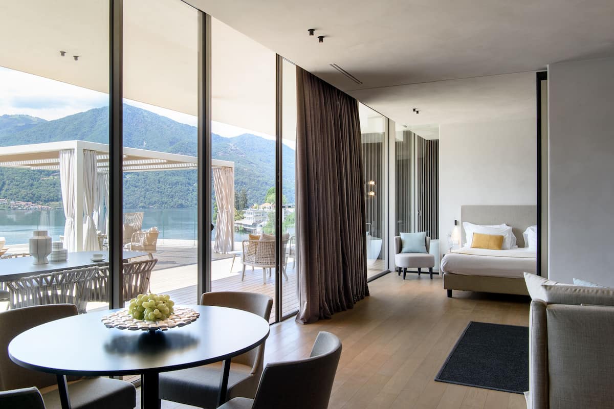 Een moderne hotelkamer met balkon, bed, zithoek en uitzicht op de bergen.