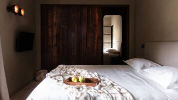 Una cama bien hecha con una colcha blanca y una bandeja de madera con manzanas.