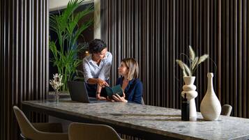A modern meeting room with a long table, chairs, and a laptop.