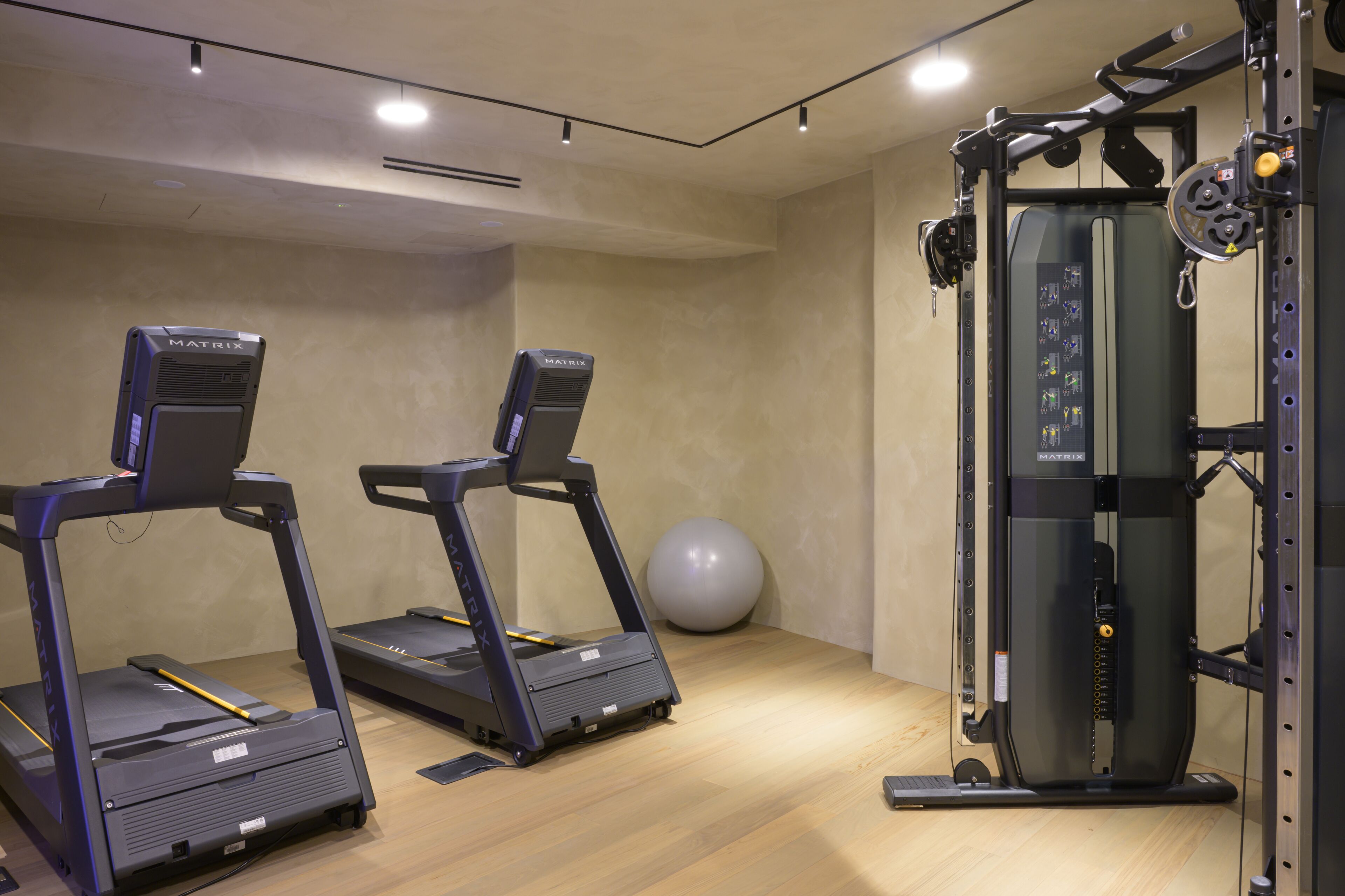 Een sportschool met loopbanden, een hometrainer en een krachttrainingapparaat.