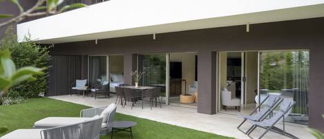 A modern two-story house with a patio area featuring outdoor furniture and a lawn.