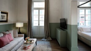Ett vardagsrum med en soffa, ett soffbord, en tv och en dörr med gardiner.
