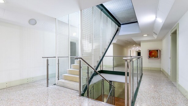 A modern interior with a glass staircase, a polished floor, and a framed artwork on the wall. - GuestHost - Molino Stucky Residence Bragosso Suite (Venezia)