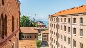 A view of a cityscape with brick buildings, a clear sky, and a distant body of water. - GuestHost - Molino Stucky Residence Bragosso Suite (Venezia)