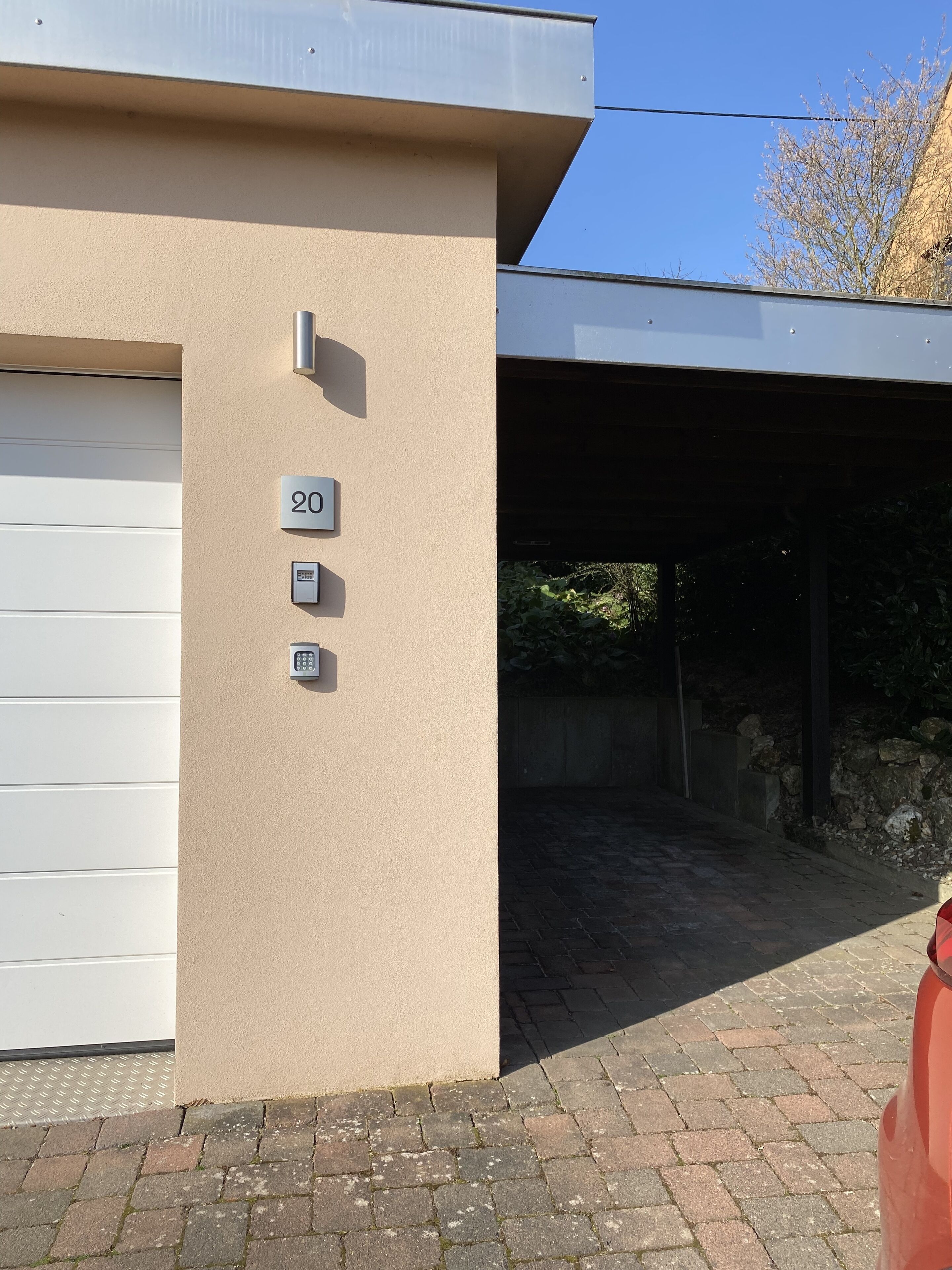 A building with a beige exterior, a garage door, and a number '20' sign.