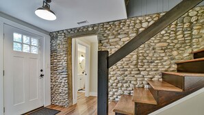 Una escalera con un muro de piedra, escalones de madera y una puerta blanca.