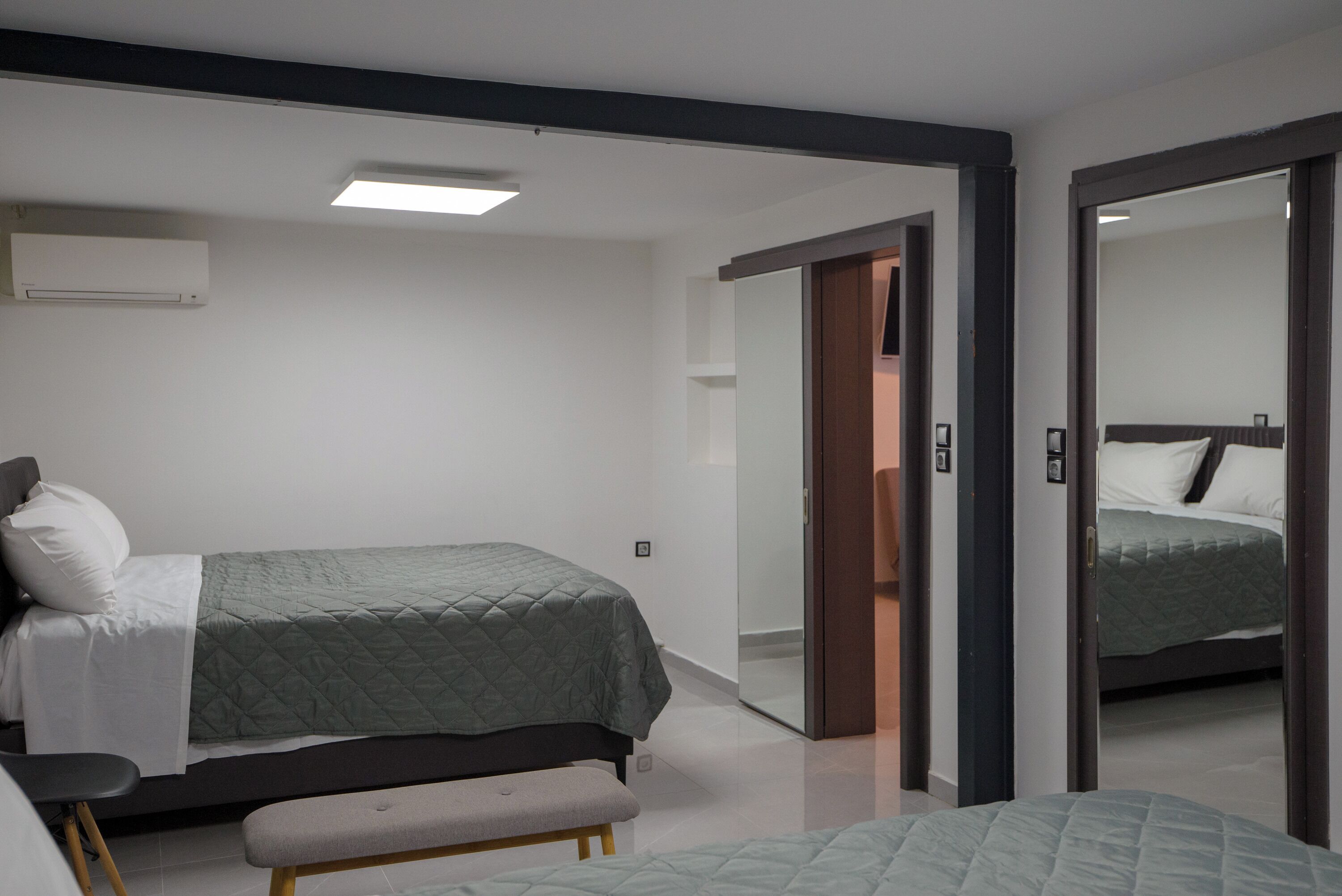 Un dormitorio moderno con cama, banqueta y armario.