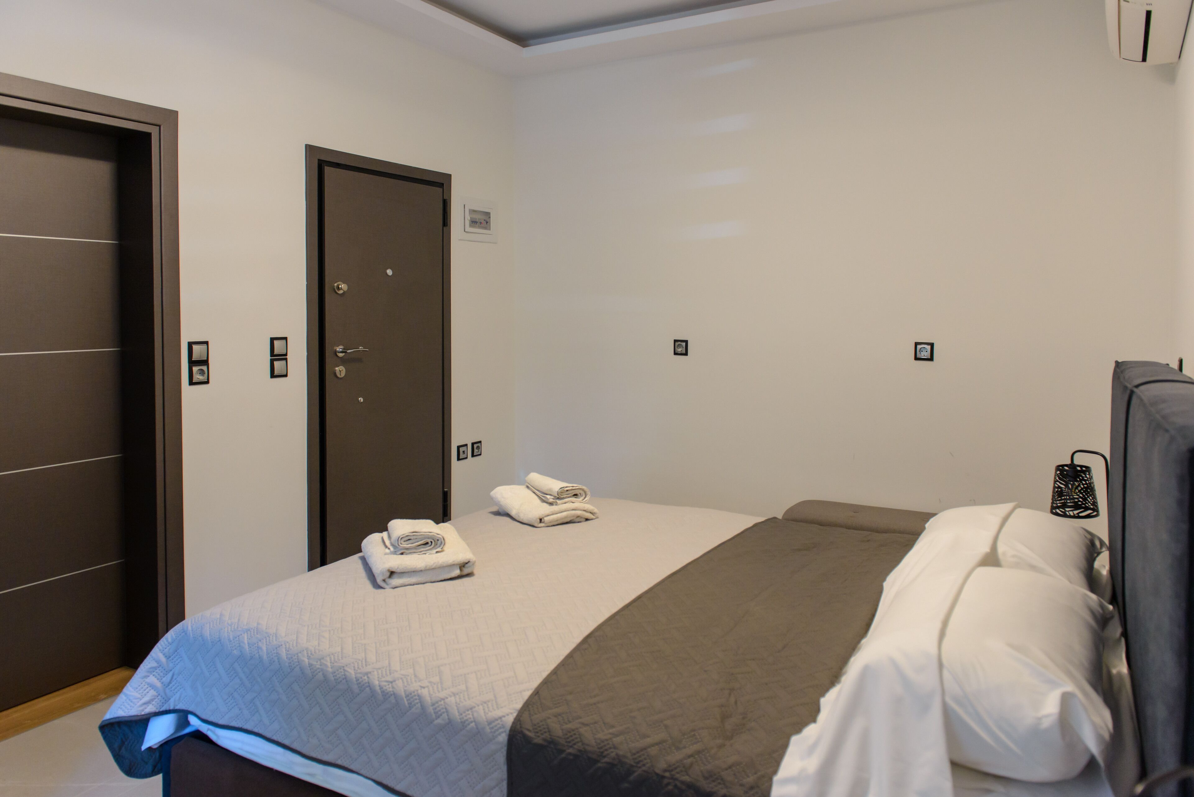 Ein Hotelzimmer mit einem Bett, zwei Türen und einer Wand-Klimaanlage.