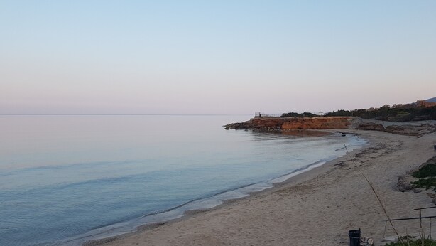 Une plage avec un promontoire rocheux et une vue dégagée sur la mer.