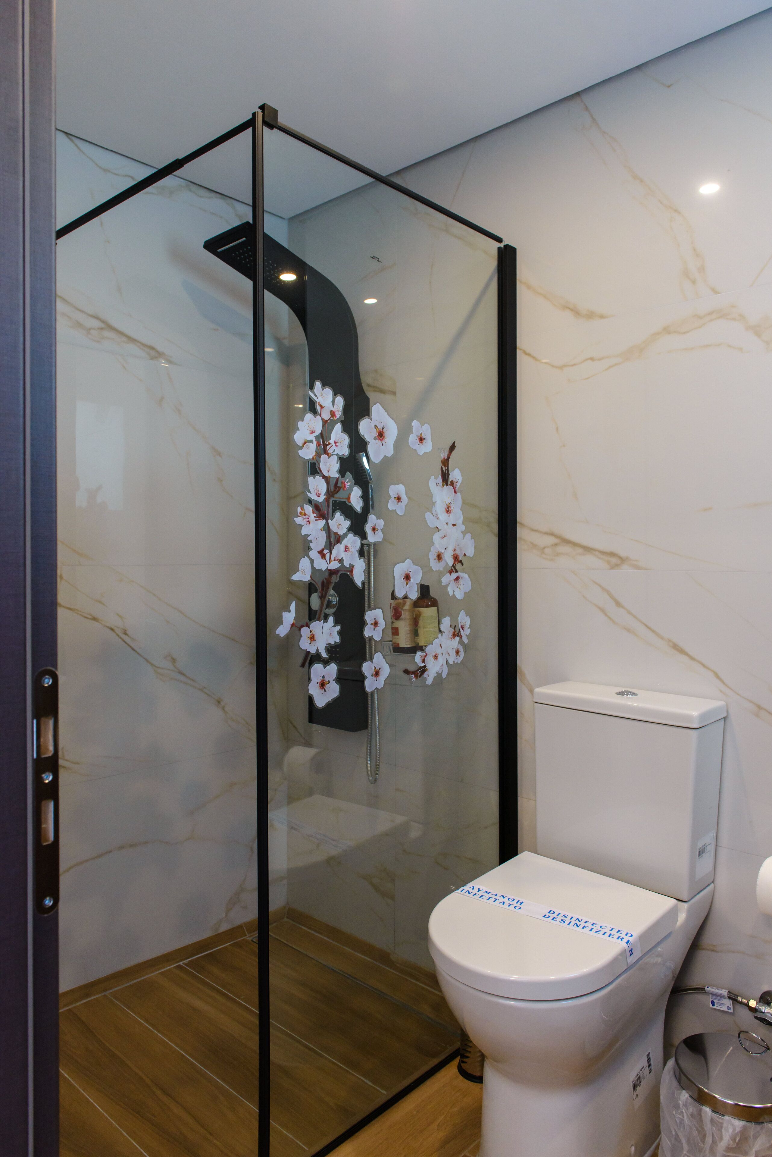 Een moderne badkamer met een douchecabine van glas, een toilet en een marmeren wand.