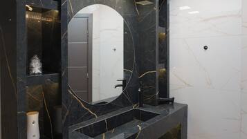 A modern bathroom with a black marble vanity, a large mirror, and a skylight.