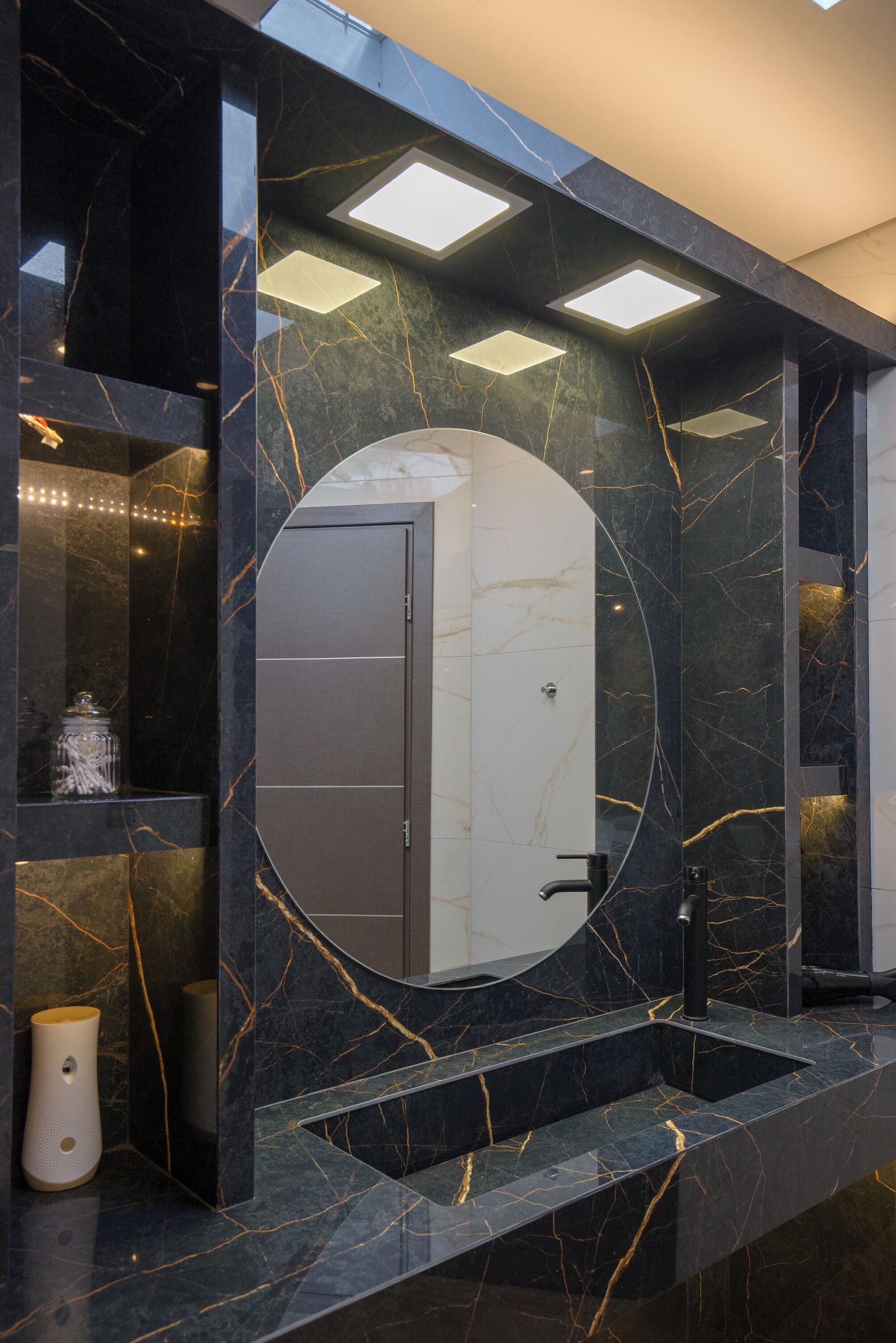 Un baño moderno con tocador de mármol, lavabo integrado y un espejo grande.