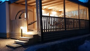 A wooden cabin with a porch, a staircase, and a railing. - Newly built mobile home by the sea with large terrace (Drage)