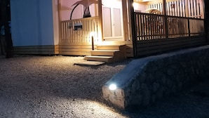 A small, single-story wooden structure with a porch and a covered outdoor area. - Newly built mobile home by the sea with large terrace (Drage)