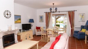 Una sala de estar con chimenea, televisor, sofá y comedor.