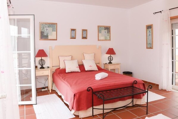 A bedroom with a bed, two bedside tables, a window, and a door.