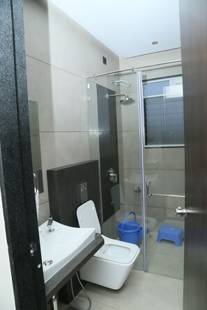 A modern bathroom with a glass-enclosed shower, a white sink, and a black countertop.