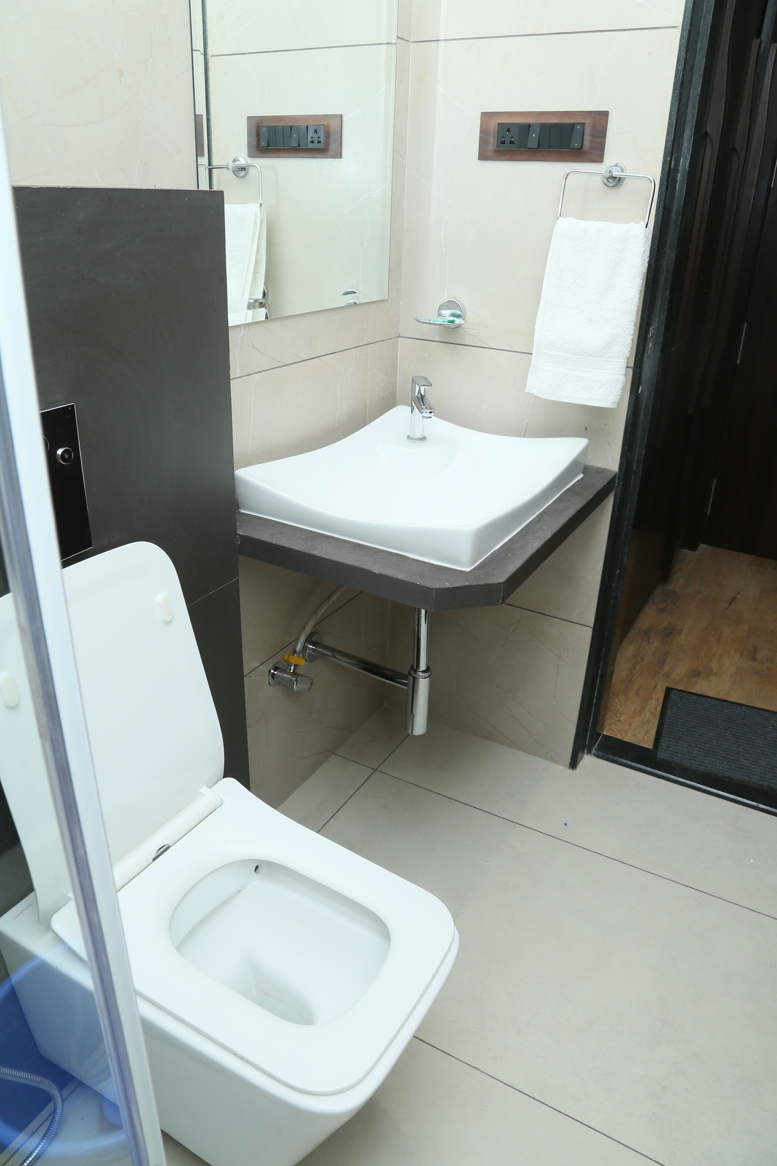 Un baño moderno con inodoro blanco, lavamanos y espejo.