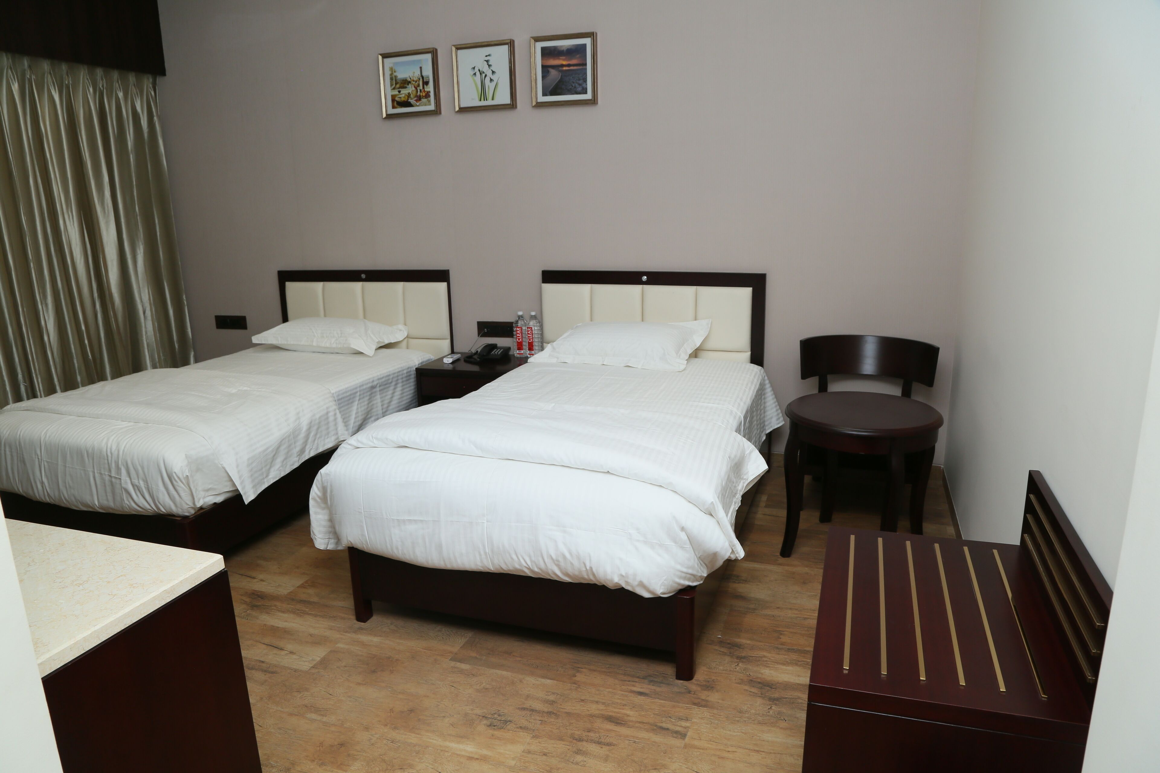 Habitación de hotel con dos camas, un escritorio, una silla y una mesita.