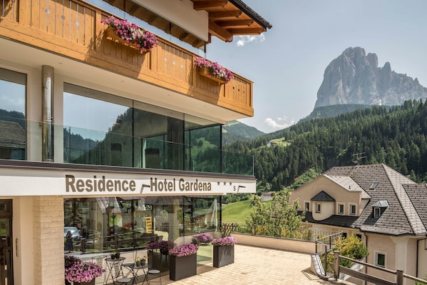 A hotel with a balcony, large windows, and a mountain view.