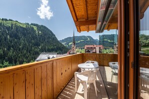 A wooden balcony with a view of a mountain and a church.