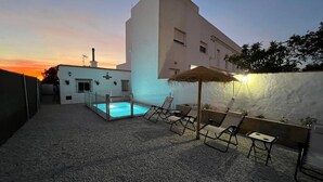 A rooftop pool area with lounge chairs, a pool, and a building in the background.