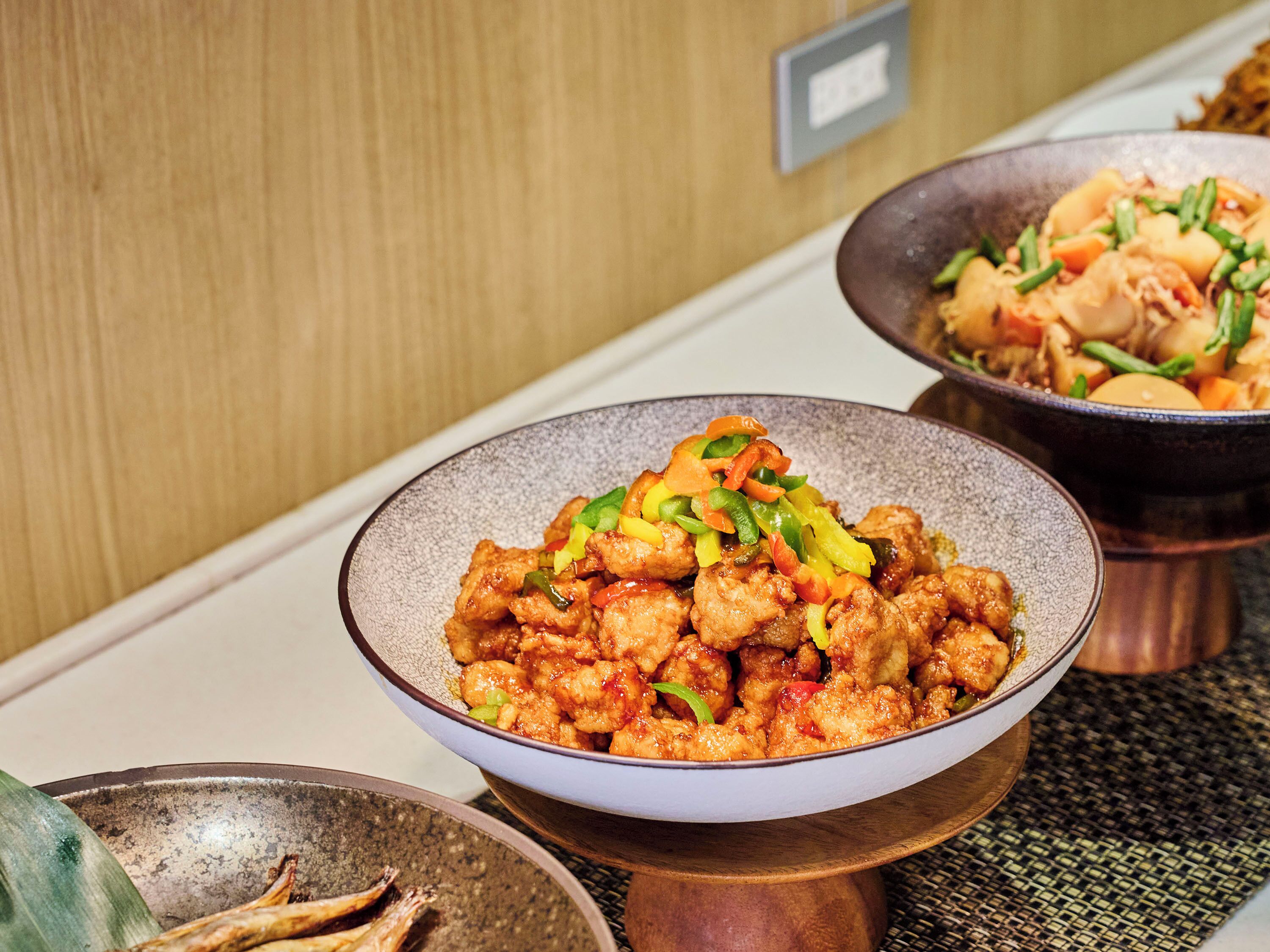 A dining table with multiple dishes, including a bowl of stir-fried vegetables and meat, and another dish with a different presentation.