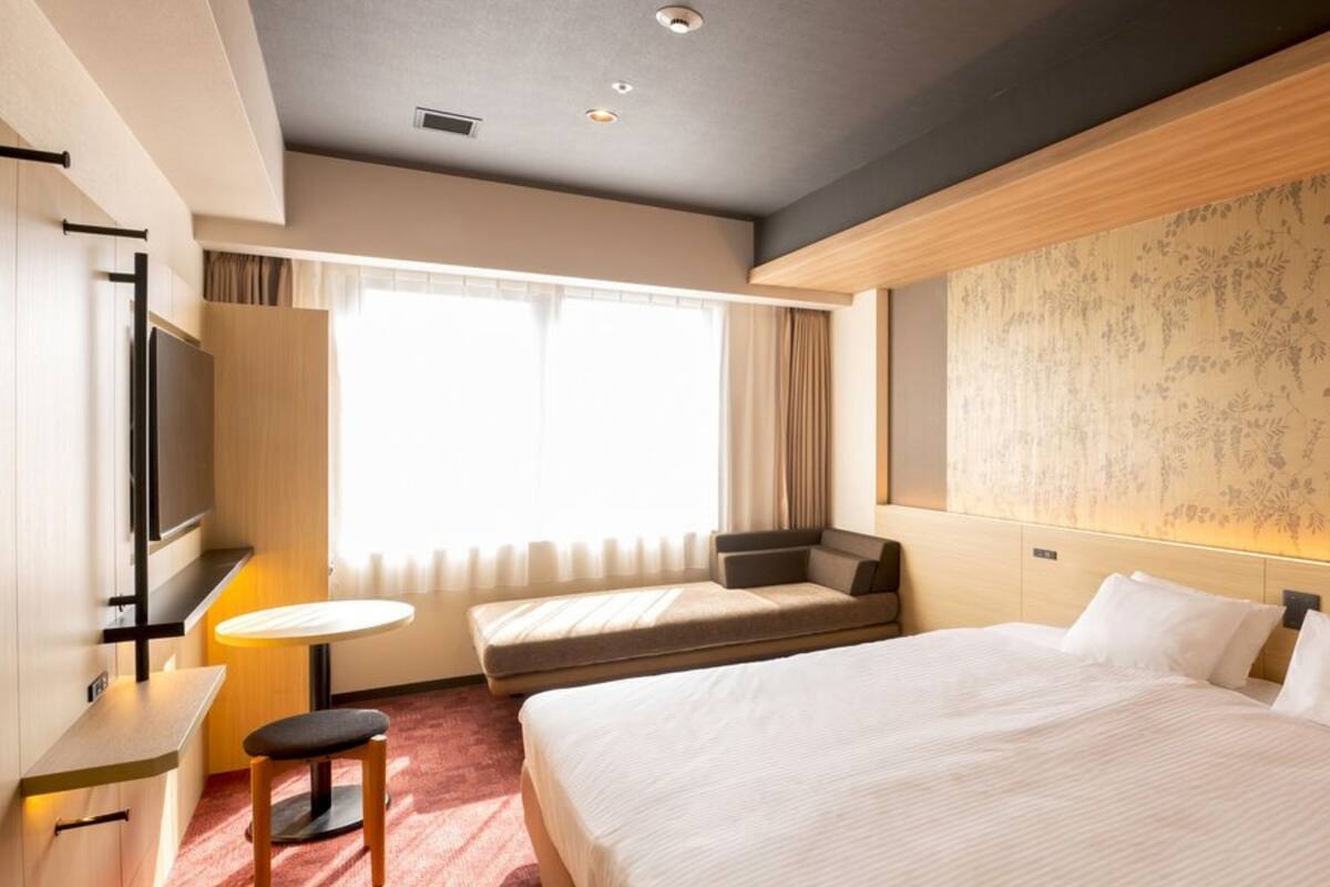 Une chambre d’hôtel avec un grand lit, un canapé, une petite table et un téléviseur.
