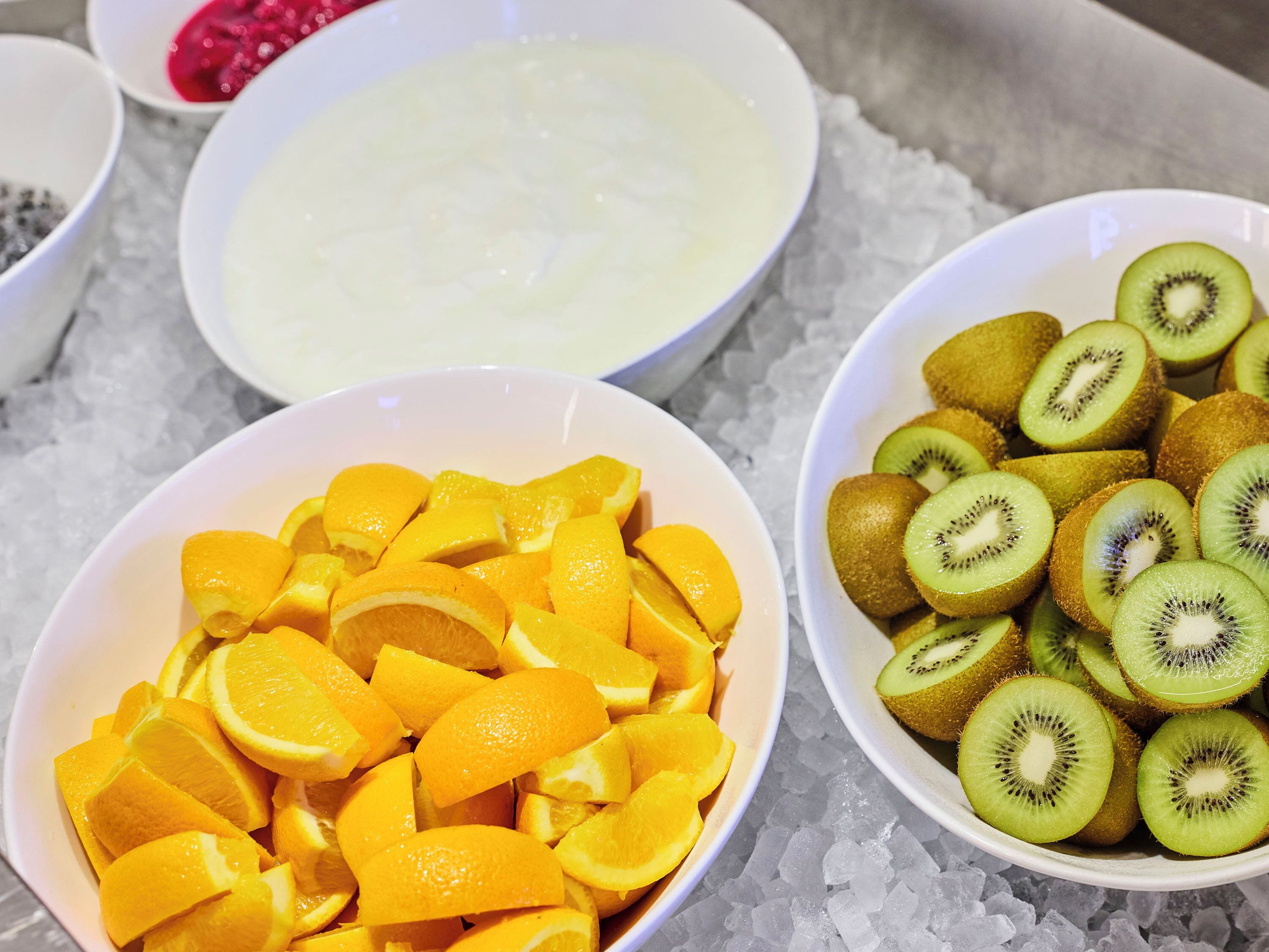 Taças com fatias de laranjas e kiwis sobre gelo.