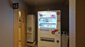 A vending machine with a Coca-Cola logo, a water dispenser, and a trash bin.