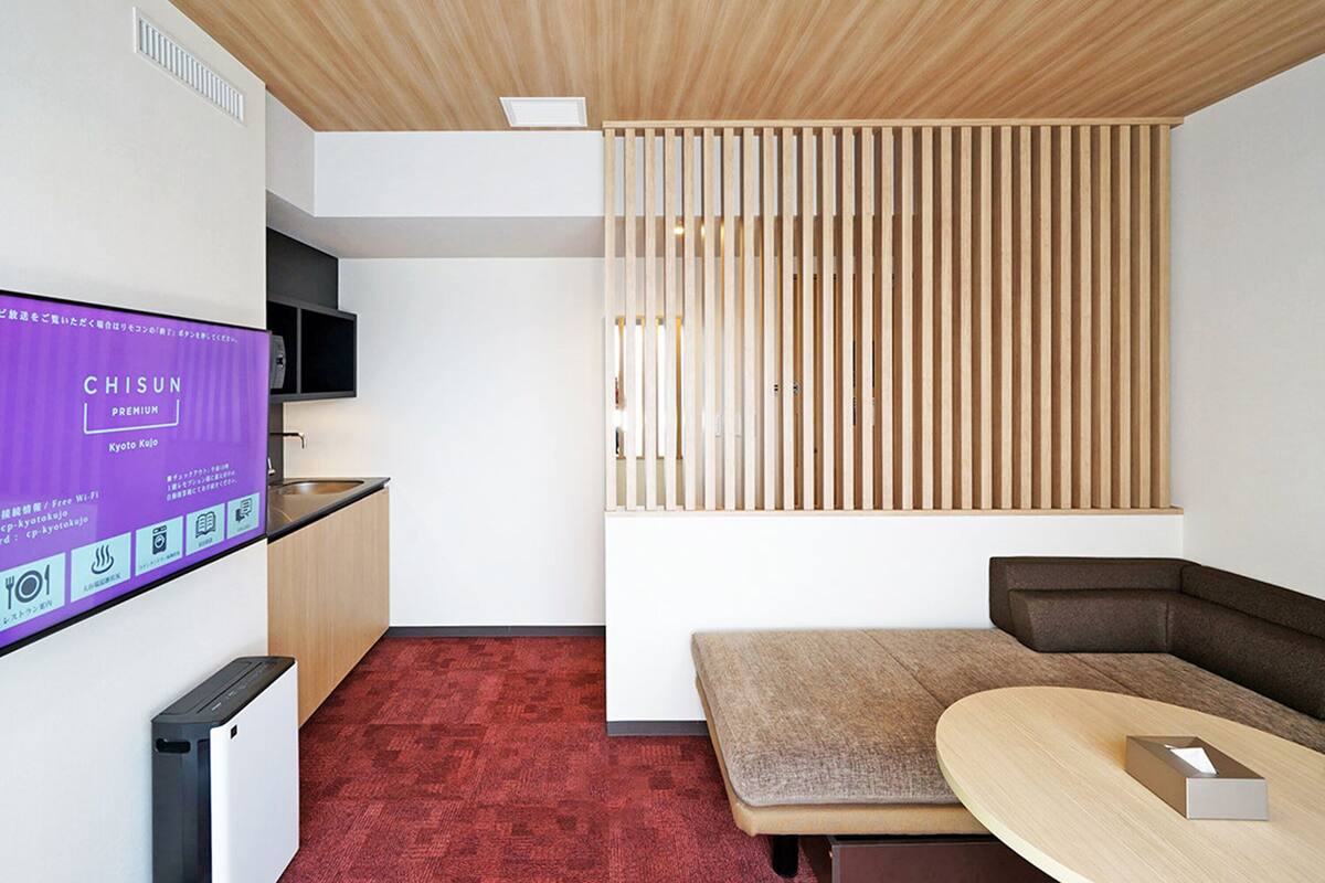 Une chambre moderne dotée d’une cloison en lattes de bois, d’un téléviseur à écran plat, d’un canapé et d’une petite table.