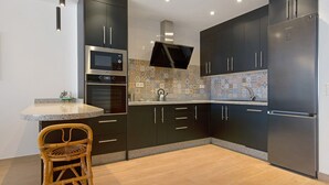 A modern kitchen with dark cabinets, stainless steel appliances, and a patterned backsplash. - Vacation Home Falco 1 close to the Beach with Sea View, Whirlpool & Wi-Fi (Corralejo)