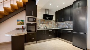Una cocina moderna con armarios oscuros, un refrigerador de acero inoxidable, un microondas y un horno empotrado.