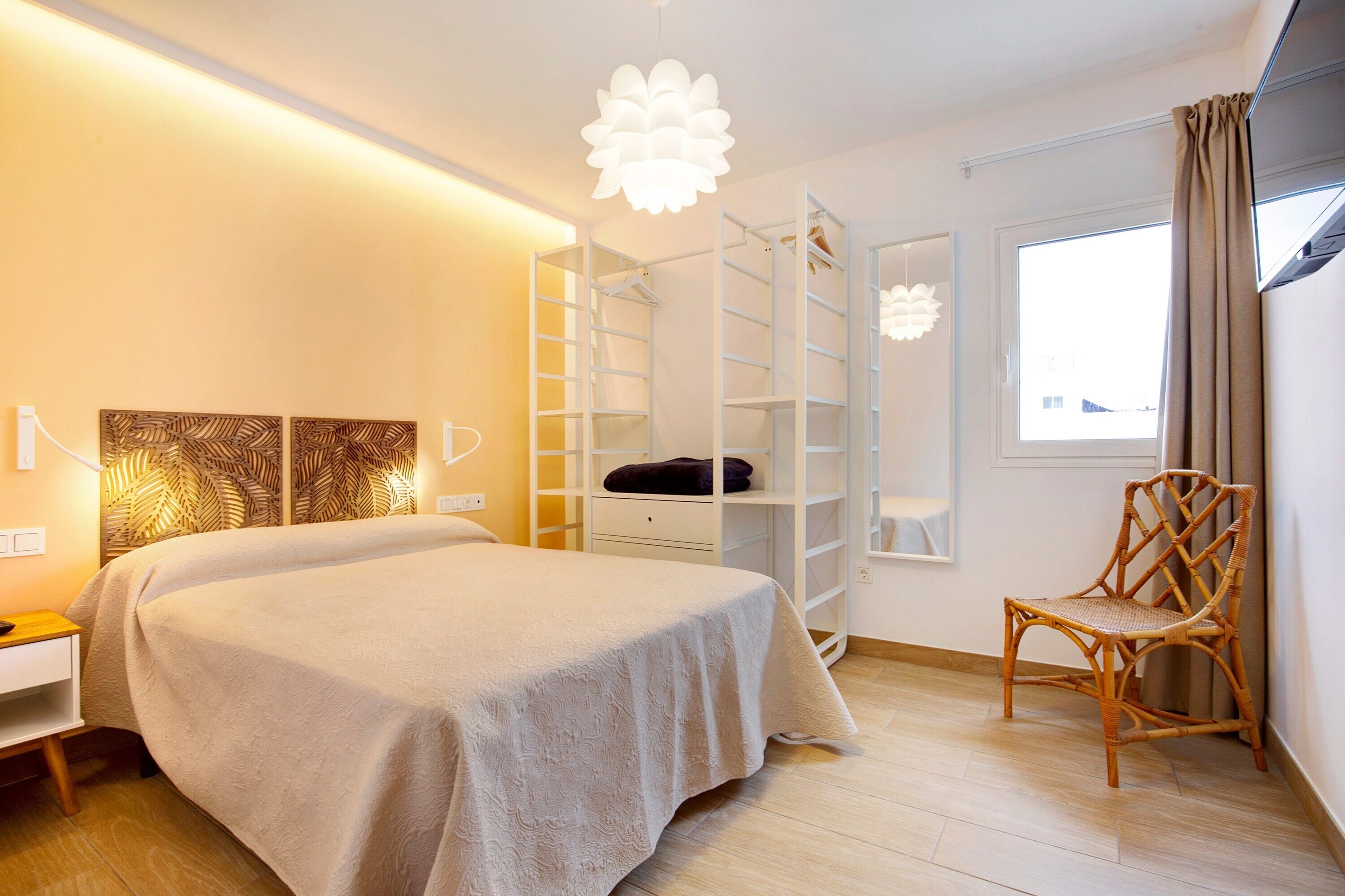 A bedroom with a bed, a wardrobe, a chair, and a window.