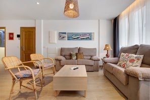 Un salon moderne avec un canapé, deux fauteuils, une table basse et des œuvres d’art accrochées au mur.