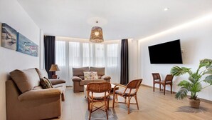 Una sala de estar moderna con un sofá, sillas, un televisor y una planta.