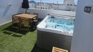 Una terraza en la azotea con hidromasaje, una mesa con sillas y una sombrilla.