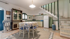 Una cocina con una mesa de comedor, sillas, microondas y una escalera.