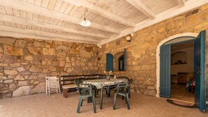Una habitación con paredes de piedra, techo de madera, una mesa con sillas y un banco.