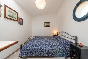 Un dormitorio con cama, mesita de noche, lámpara y ventana con vistas.