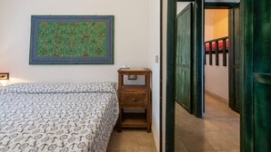 Ein Schlafzimmer mit Bett, Nachttisch, Wandbild und einem Flur, der zu einer Treppe führt.