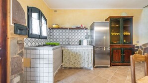 Eine Küche mit gefliestem Rückspritzschutz, einem eingebauten Herd, einem Kühlschrank und einem Holzkasten.